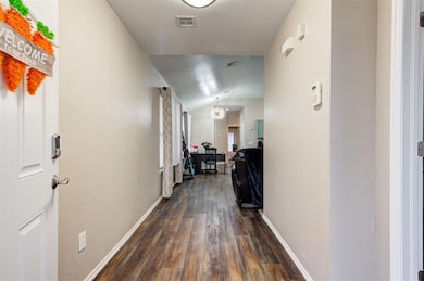 Hallway with dark wood-type flooring, visible vent