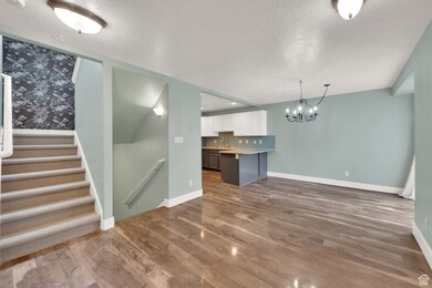 Kitchen featuring a peninsula, light countertops, white cabinetry, pendant lighting, and a textured ceiling