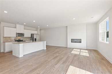 Kitchen featuring stainless steel appliances, an island with sink, tasteful backsplash, white cabinets, and a sink