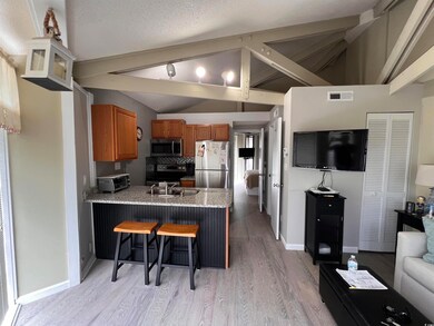 Kitchen featuring a breakfast bar, brown cabinetry, light wood-type flooring, appliances with stainless steel finishes, and a peninsula