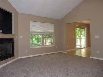 Living room has a vaulted ceiling and features a gas log fireplace.