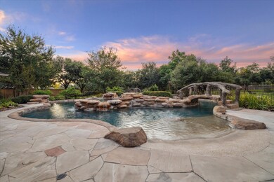 A raised spa and multiple waterfalls highlight the front pool area with a bridge leading you to landscaped pathways along the lazy river and through the yard.