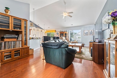 Living room with hardwood / wood-style floors, ceiling fan, and high vaulted ceiling