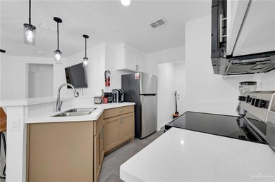 Kitchen with freestanding refrigerator, a sink, range with electric cooktop, light countertops, and a peninsula