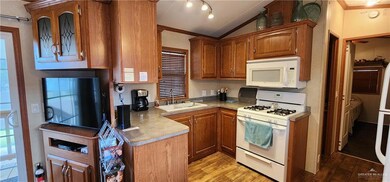 Kitchen with light hardwood / wood-style flooring, white appliances, rail lighting, sink, and ornamental molding