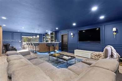 Oversized Entertainment Room/Bar, island designed with custom oak wall painted in blue with custom wall paneling, Lumary smart ambient LED lighting on both bar and ceiling, built in bar area with beverage fridge and ice maker. Walk right out to pool deck. Cabana Bath also located in this lower level lounge.