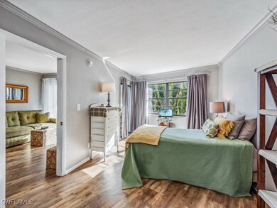 Bedroom featuring crown molding wood-style floorin
