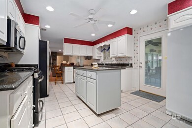Kitchen with stainless steel appliances, a ceiling fan, white cabinetry, light tile patterned floors, and recessed lighting
