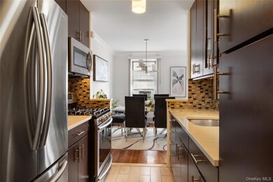 Kitchen with appliances with stainless steel finishes, pendant lighting, dark brown cabinets, ornamental molding, and light stone counters