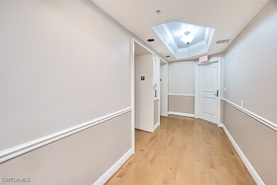 Hall featuring a raised ceiling and light hardwood