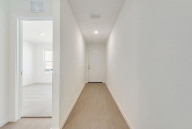 Hallway featuring light wood finished floors and baseboards