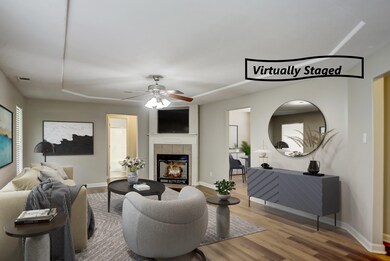 Living room featuring ceiling fan, a tiled fireplace, and wood-type flooring
