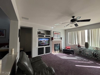Carpeted living area featuring a ceiling fan, buil