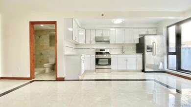 Kitchen with stainless steel appliances, white cabinets, light countertops, and inlaid floor details