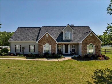 Cape cod home with roof with shingles, a front lawn, stone siding, covered porch, and fence