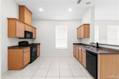 Kitchen featuring sink, light tile patterned floors, and black appliances