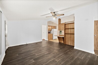Unfurnished living room with lofted ceiling, dark wood-type flooring, a ceiling fan, and a textured ceiling
