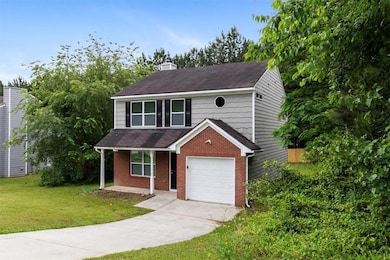 View of front of property with a front yard, a chimney, brick siding, driveway, and roof with shingles