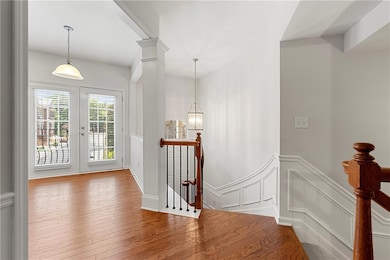 Foyer with wood-type flooring, a decorative wall, wainscoting, and french doors