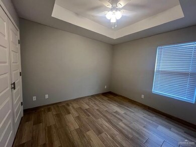 Spare room with a raised ceiling, wood finished floors, and ceiling fan