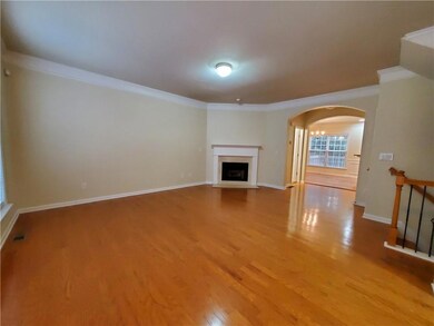 Unfurnished living room with crown molding, arched walkways, light wood-style flooring, a fireplace with flush hearth, and baseboards