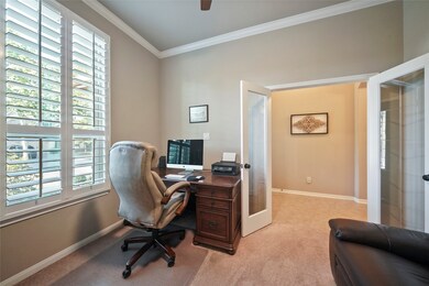 The office sits at the front of the home overlooking the lush front yard. Notice shutters and French doors.