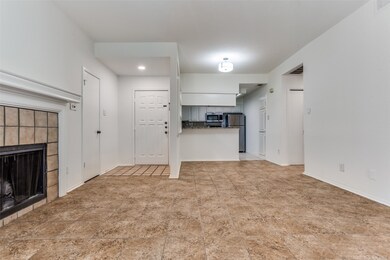 Unfurnished living room featuring a tiled fireplace and light tile patterned flooring