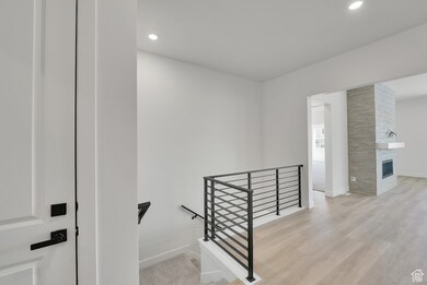 Stairway featuring wood finished floors, a fireplace, and recessed lighting