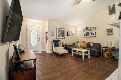 Living room with vaulted ceiling, dark wood-type flooring, and a ceiling fan