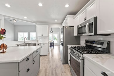 Kitchen with stainless steel appliances, tasteful backsplash, ceiling fan, white cabinetry, and recessed lighting