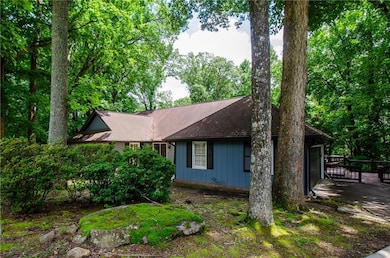View of property exterior featuring a wooden deck, an attached garage, driveway, and roof with shingles