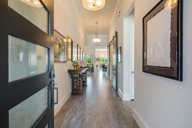 Welcome inside! Notice the gorgeous tile flooring, high ceiling, beautiful light fixtures, double barn doors on the right leading into the home office. The secondary bedrooms are located at the front of the home.