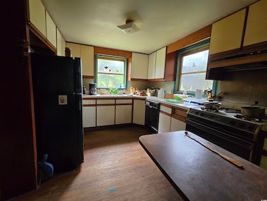 Kitchen featuring black appliances, ventilation hood, wood finished floors, and plenty of natural light