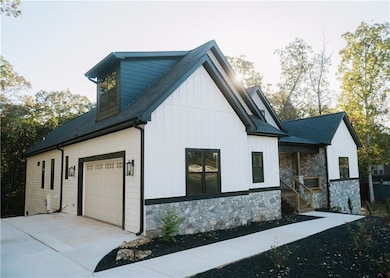 View of home's exterior with roof with shingles, stone siding, board and batten siding, and a porch