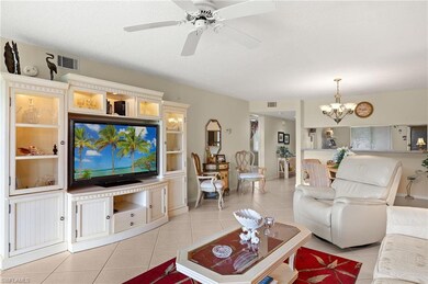 Living room featuring visible vents, light tile patterned floors, and ceiling fan with notable chandelier