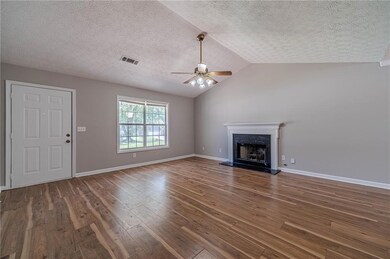 Unfurnished living room with a ceiling fan, hardwood / wood-style floors, a premium fireplace, a textured ceiling, and lofted ceiling