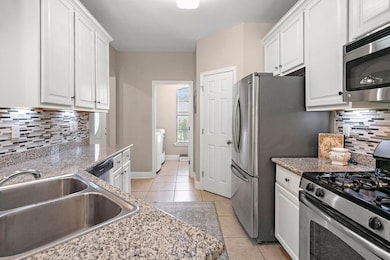 Kitchen offers white cabinetry, granite countertop
