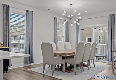 Dining space with light wood finished floors, plenty of natural light, and a chandelier