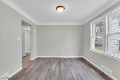 Spare room featuring baseboards, visible vents, and wood finished floors