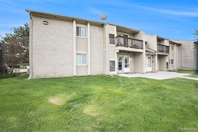 Rear view of property with a patio area, a balcony, a yard, and brick siding