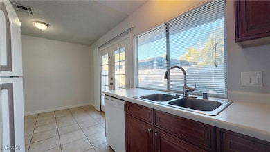 Kitchen with light countertops, white appliances, light tile patterned floors, a textured ceiling, and french doors