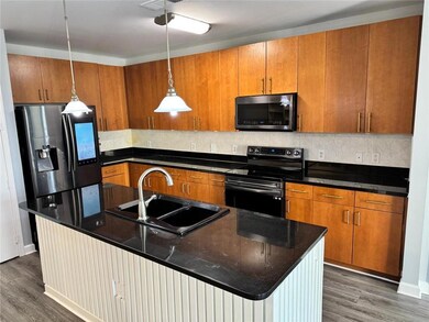 Kitchen with appliances with stainless steel finishes, dark hardwood / wood-style floors, a center island with sink, and sink