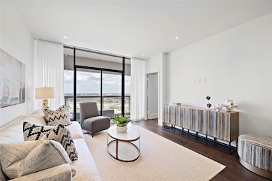 The main living area is drenched in natural light that pours through a wall of glass and sliding door onto balcony.