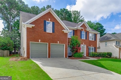 Colonial home featuring driveway, an attached garage, a front lawn, and brick siding