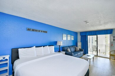 Bedroom with a textured ceiling, a textured wall, access to outside, and wood finished floors