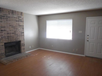 Unfurnished living room with baseboards, a brick 