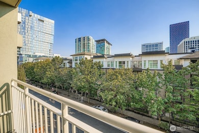 South facing covered balcony overlooking downtown Bellevue with tree-lined streets and city views.