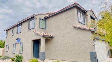 View of front of home with a tile roof, a garage,
