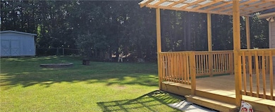 View of yard featuring a wooden deck, a storage shed, and a pergola