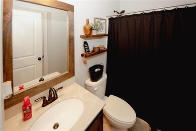 Full bath with toilet, vanity, and curtained showe